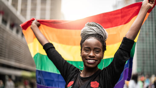 Black woman holding up a rainbow pride flag